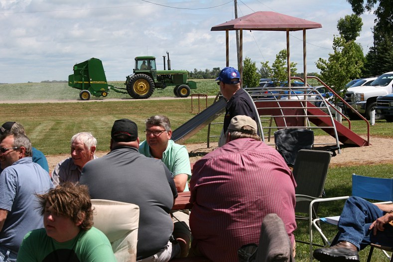 We gather in the Vesta park across the road from corn and soybean fields. Here a John Deere tractor drives past on Sunday afternoon.
