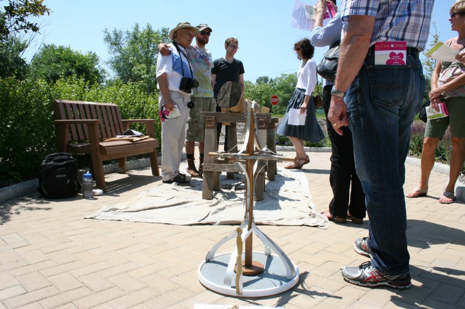 Professor Max Gimse and sculptor James Wilson pose for a photo next to the tree limb Wilson is carving. A model of the cross sits in the foreground.