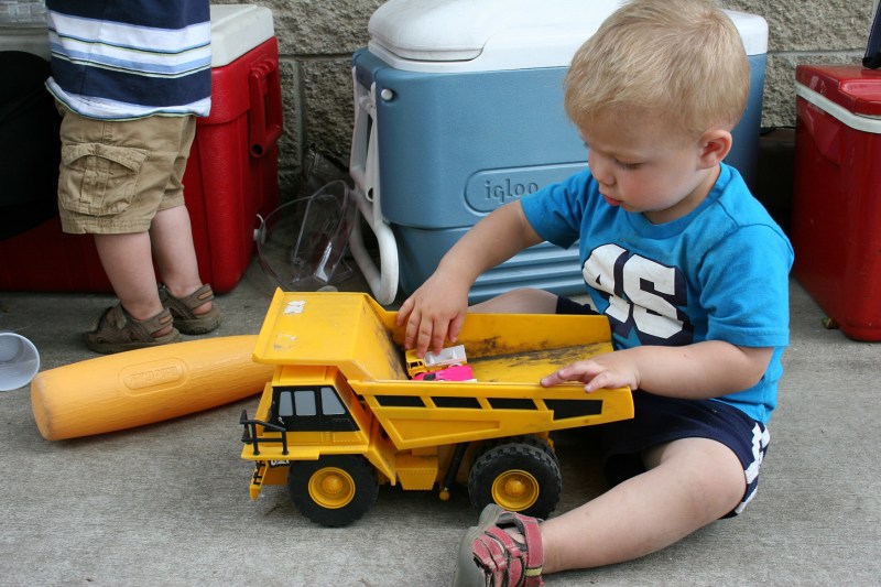 Bennett plops down and plays with his truck among the coolers.