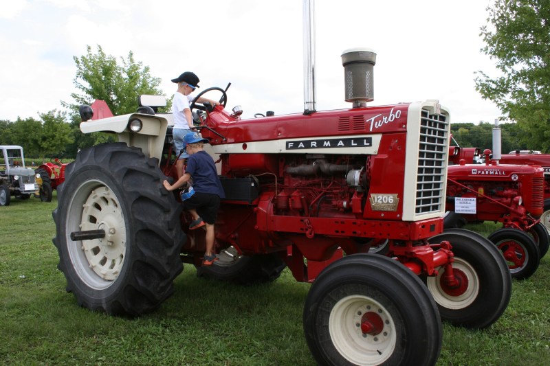 Brothers William and Jacob climb atop a Farmall.