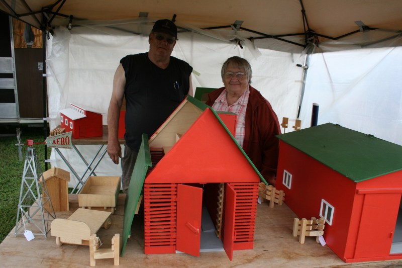 Al and Marllene Sutherland of Country Junction, Tripoli, Iowa, pose with the replica small scale farm buildings Al constructs from memory. The corn crib in the foreground includes 400 pieces and sells for $200.