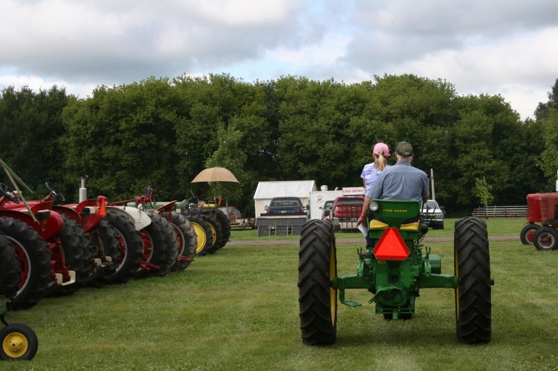 The young and the older guide a John Deere toward the parade route.