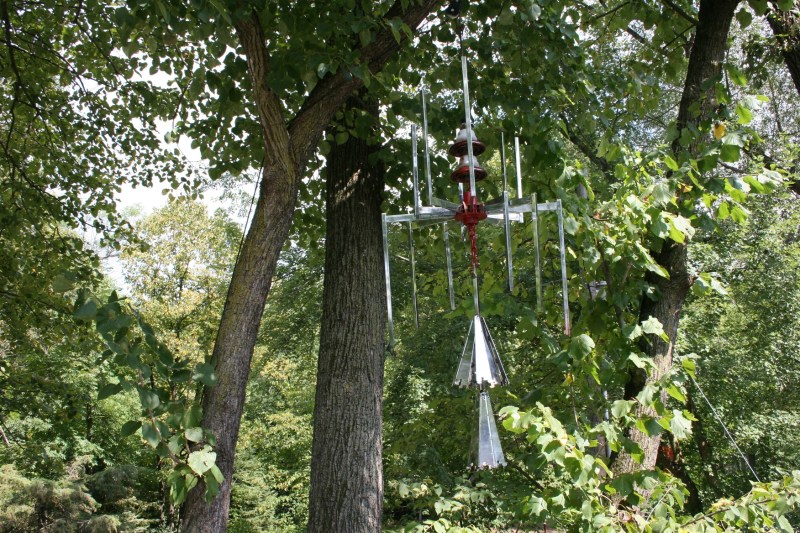 Oversized chimes crafted from discarded clothing racks (etc.) and strung high in a tree.
