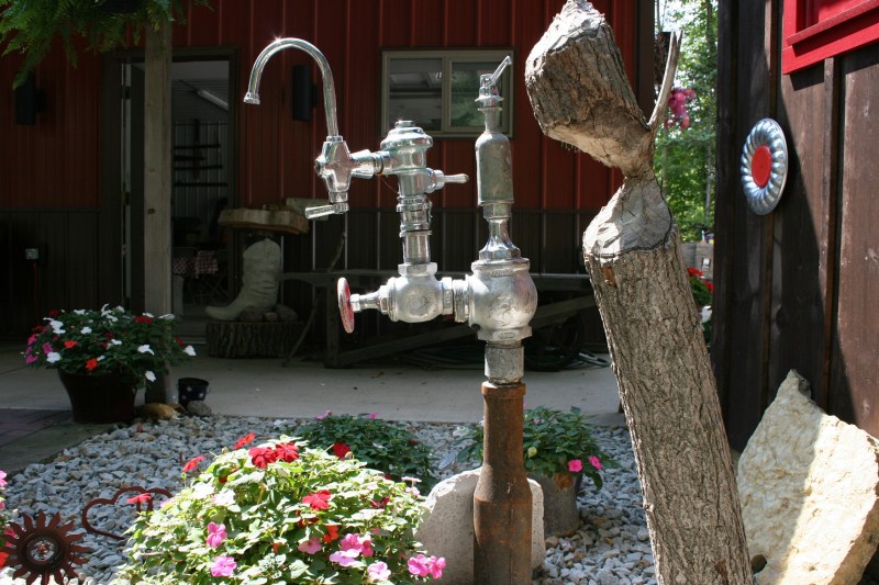 Discarded plumbing provides materials for art in a flower garden.