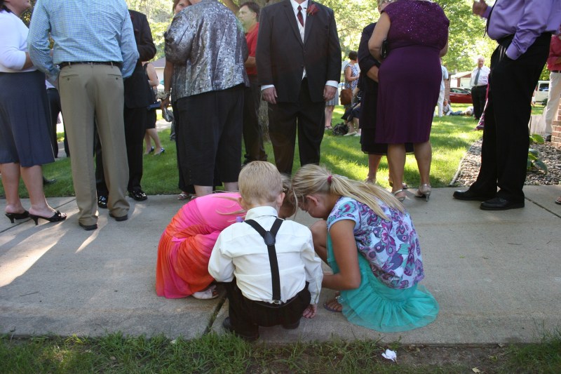 Two wedding guests and ringbearer Hank gathered on the church sidewalk next to the receiving line.