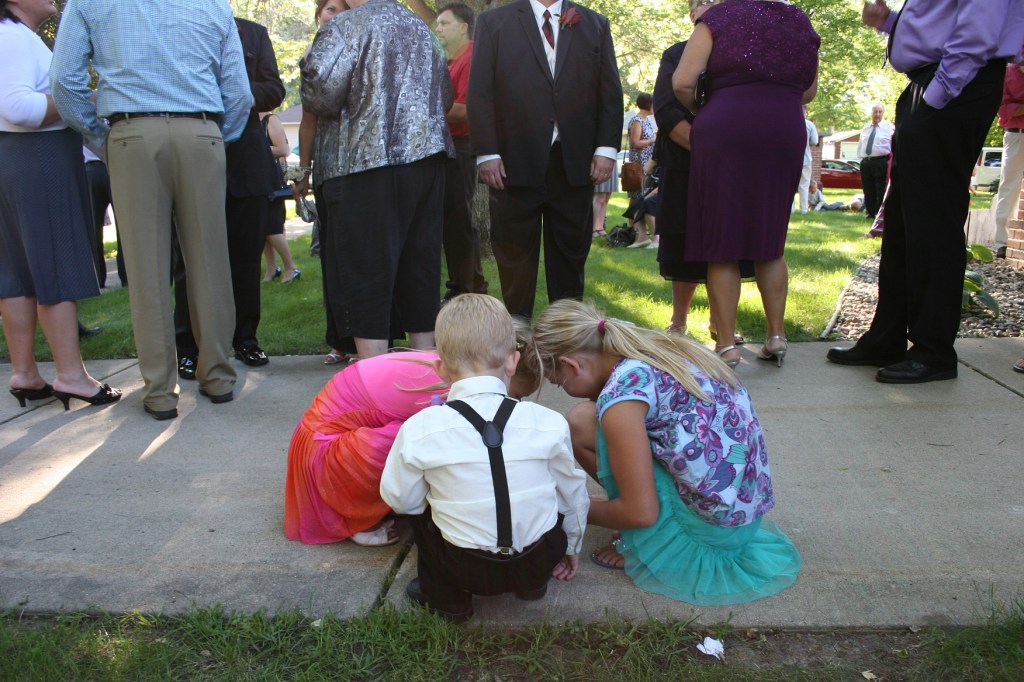 Two wedding guests and ringbearer Hank gathered on the church sidewalk next to the receiving line.
