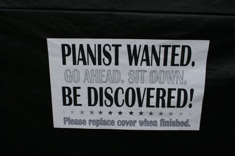 A sign invites pianists to sit down and play.