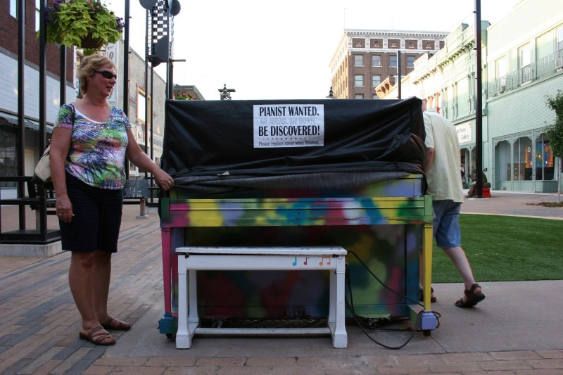 Beth Ann and Randy uncover the Plaza piano, revealing a color piano which mimics my friend's colorful shirt.