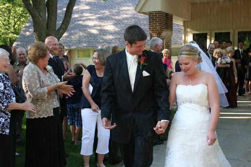 Guests shower Jared and Carlyn with birdseed as they leave the church.