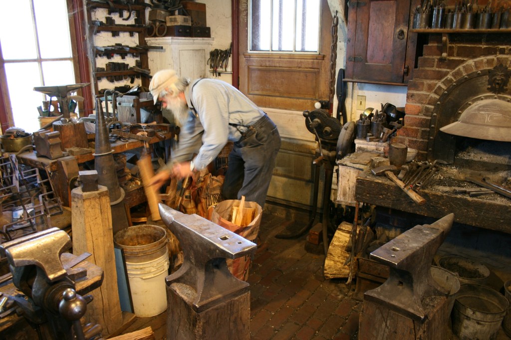 Tom splits wood in the area where he blacksmiths.