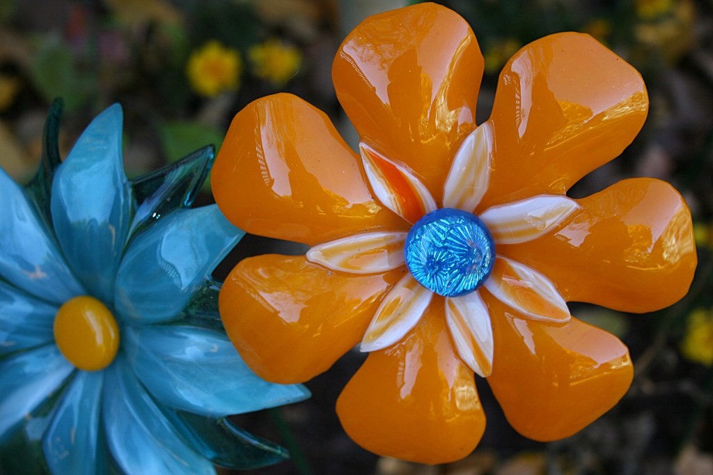 Garden art still staked outdoors copies the hues of leaves and sky.