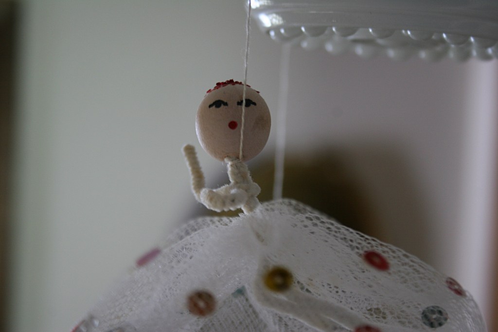 Three net angels dangle from the hallway light fixture. They are just like the angels my mom dangled from the living room doorway when I was growing up.