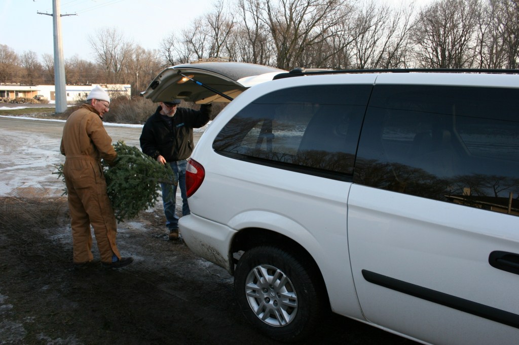Christmas tree vendor Ken Mueller helps my husband, Randy, load our old-fashioned Christmas tree into our van.