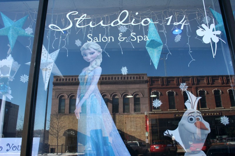 Historic buildings are reflected in the windows of Studio 14 Salon and Spa at 204 Central Avenue North. The salon created a "Frozen" display for a downtown holiday decorating contest.
