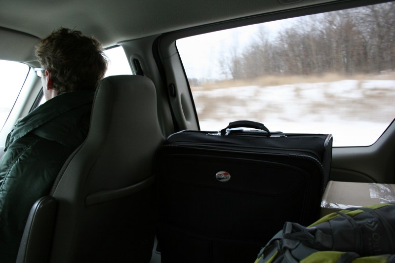The son in the front passenger seat, his suitcase and other baggage rests next to me.