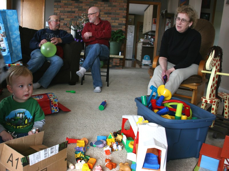 Landson opens gifts while his grandparents, left and right, and great uncle (my husband), middle watch.