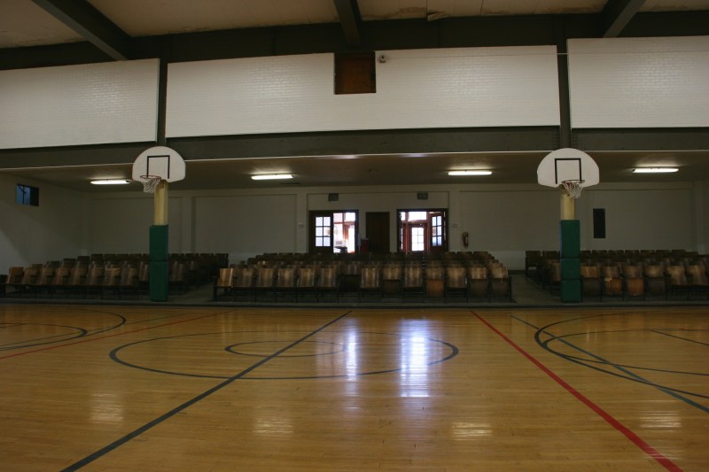 Looking across the gym floor toward the original fold-up chairs and the entry into the auditorium.