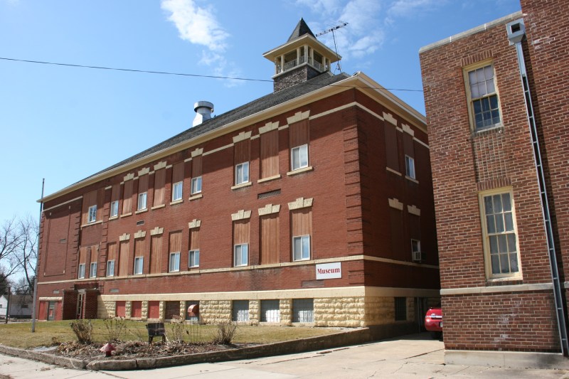 The 1902/1914 school is on the left, the 1936 gym on the right. Museum left, community center right. To enter, use the door between the buildings, in the area where the red car is parked in this photo.