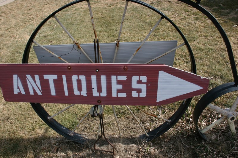 A sign propped on an antique bike directs motorists to Antiques Oronoco.