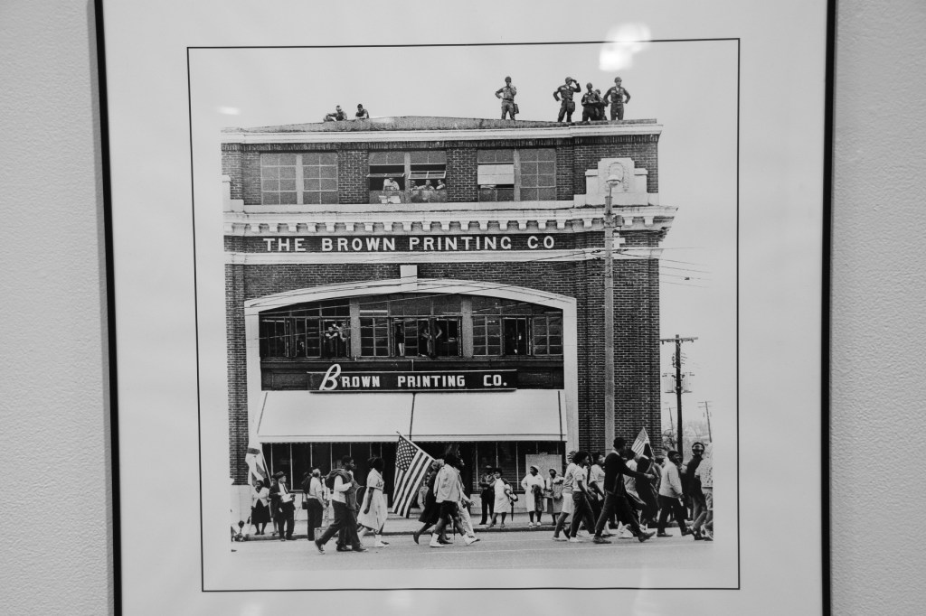 The two things I noticed in this Stephen Somerstein photo: the marcher carrying and American flag and the soldier atop the building scanning the scene with binoculars.
