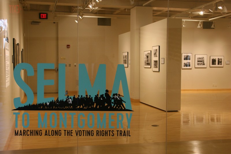 Looking through a window into an exhibit space at Flaten Art Museum.