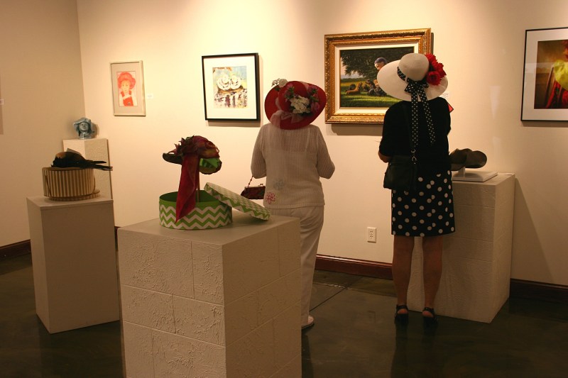 Attendees view the hat-themed exhibit in the gallery.
