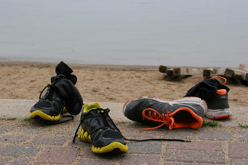 Teens' shoes abandoned along the brick pathway by the public beach.