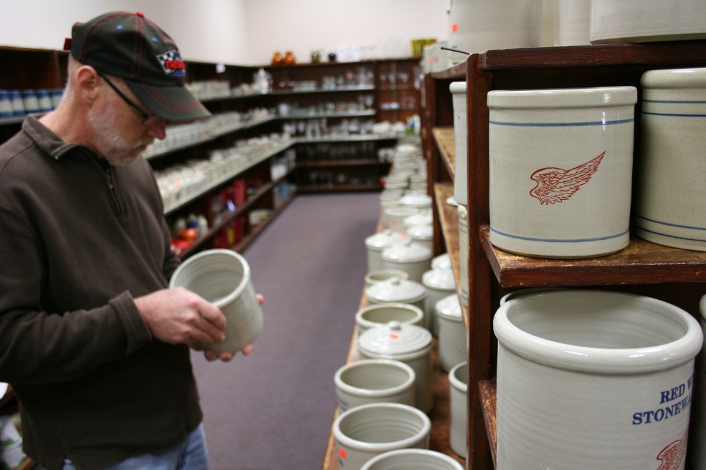My husband peruses pottery in the "seconds" section of the store.