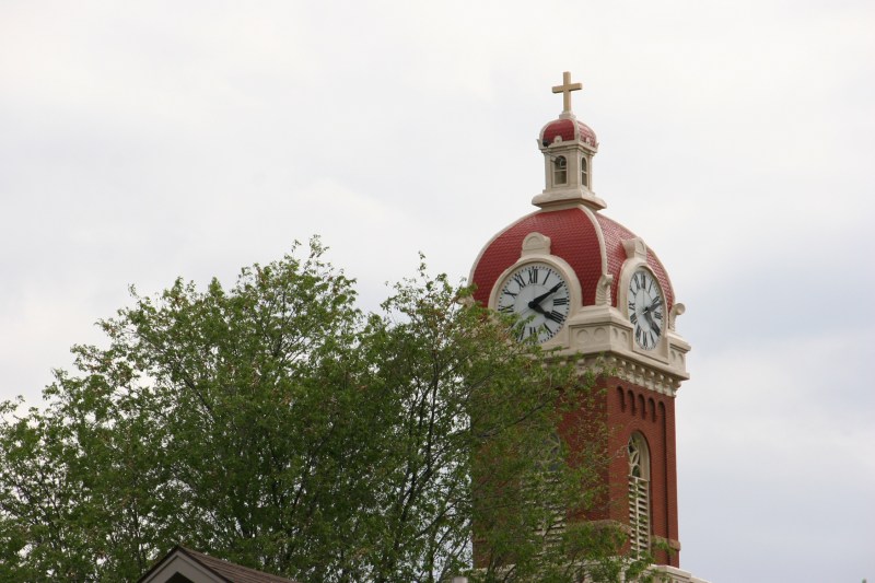 The steeple of the Cathedral of the Holy Trinity emerges from the canopy of trees in New Ulm.
