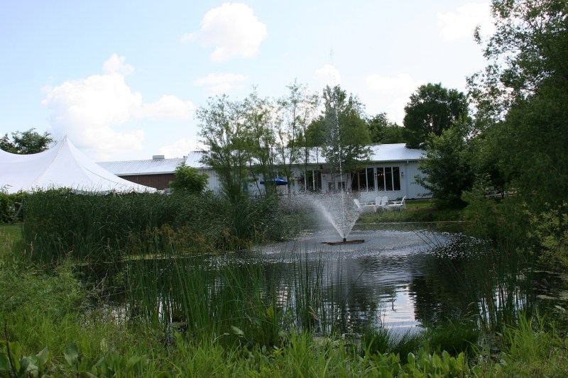 Across the pond is the tasting room deck. To the left is the tent permanently set up during the warm months for wedding and other celebrations.