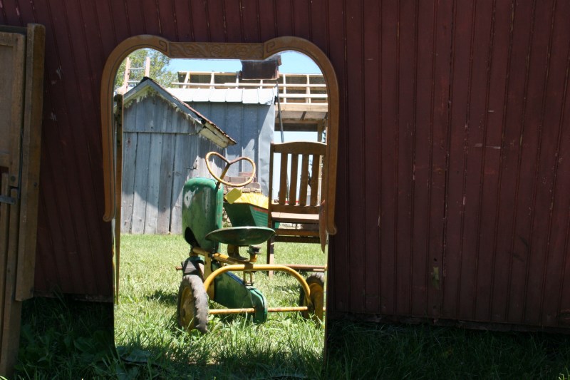 Several pedal tractors were for sale, including this one reflected in a mirror.