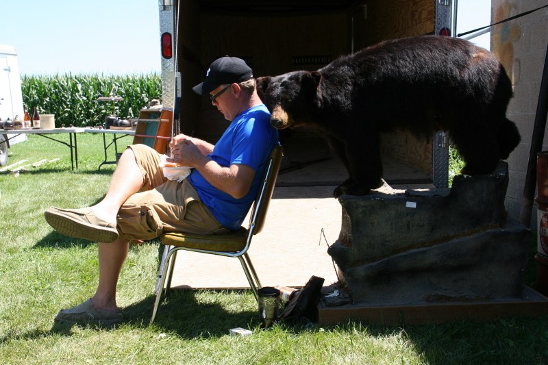 A vendor grabs lunch and settles in next to a bear he's selling.