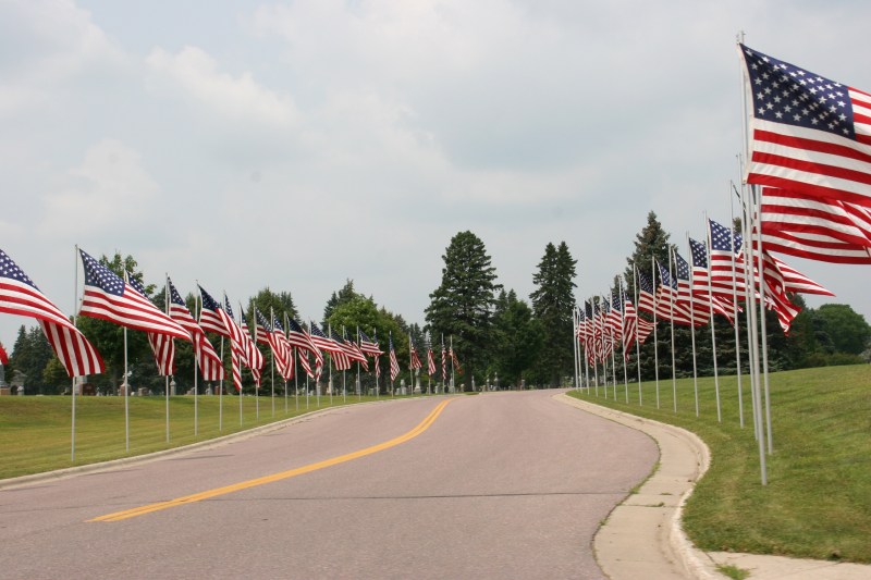 Flags line a cemetery entry along U.S. Highway 14 in New Ulm Saturday afternoon.