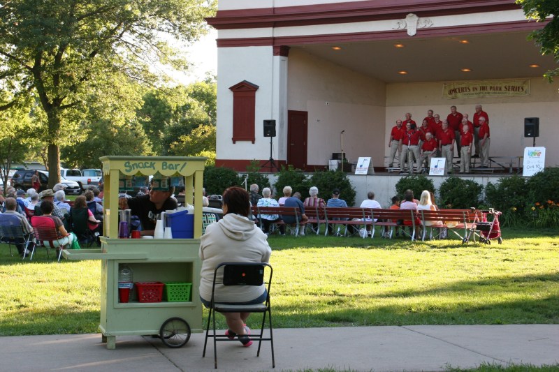 Cooper tends his business while the Lakelanders Barbershop Chorus performs in the Central Park Bandshell.