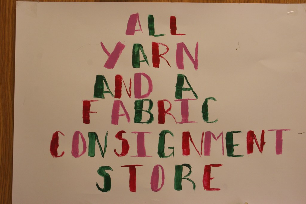 A sign in a storefront window identifies a business.