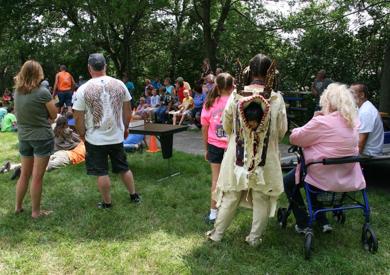 Spectators, including a reenactor from the nearby History of Trails, line the trail.