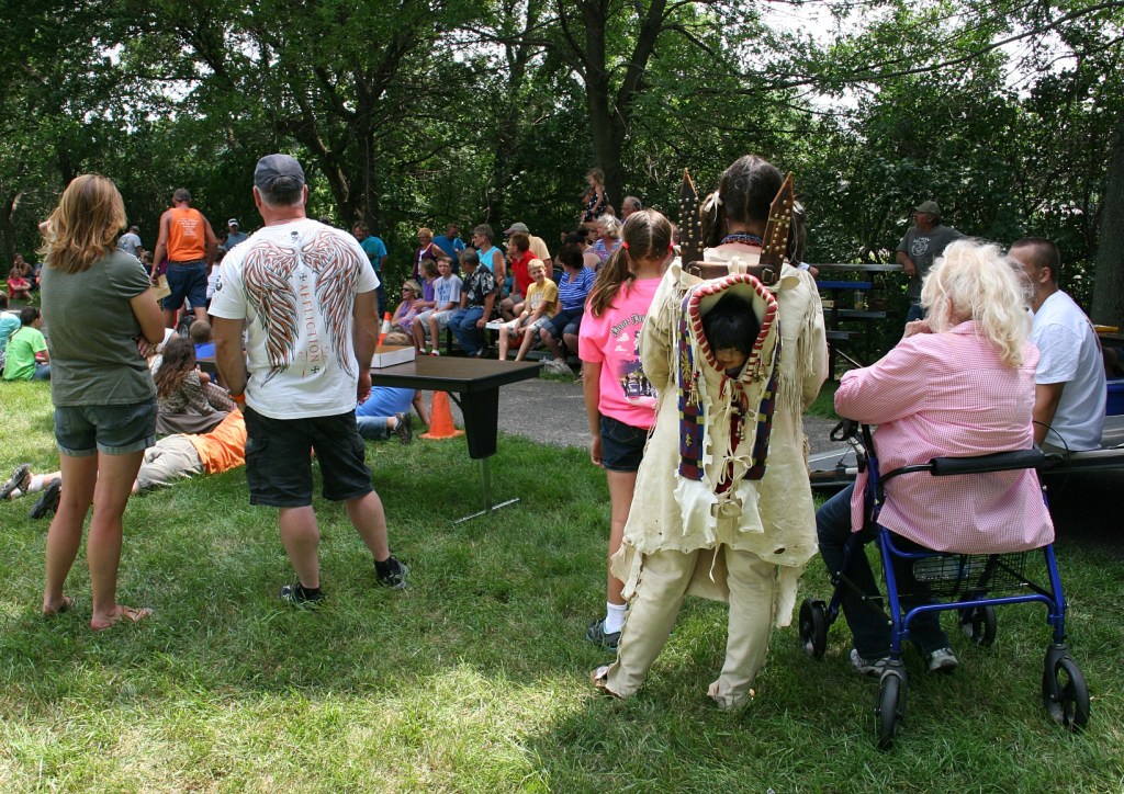 Spectators, including a reenactor from the nearby History of Trails, line the trail.