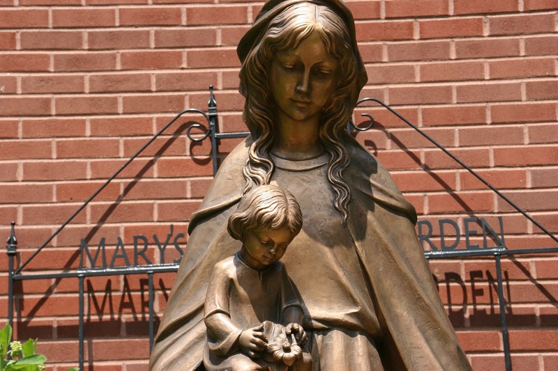 Children surround the statue of Mary in the garden.