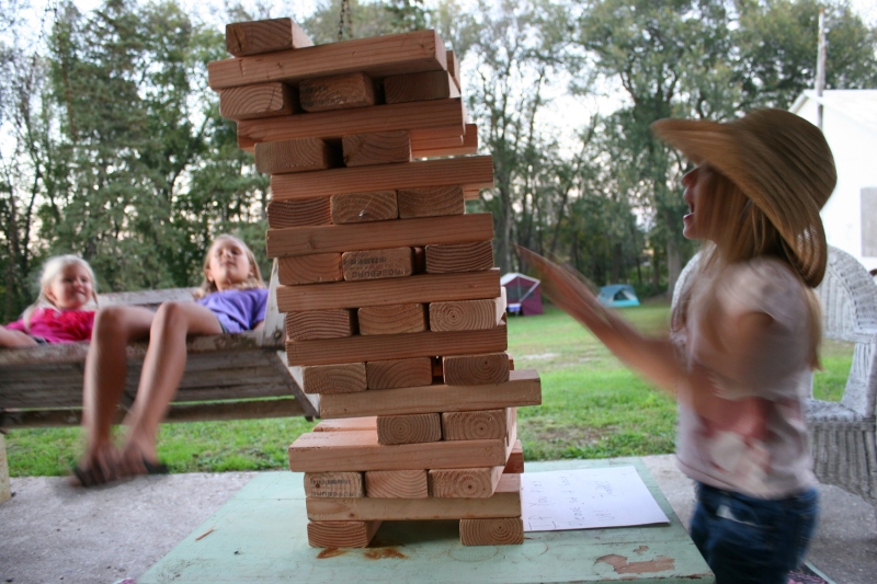 While two girls sway on a swing, another builds blocks.