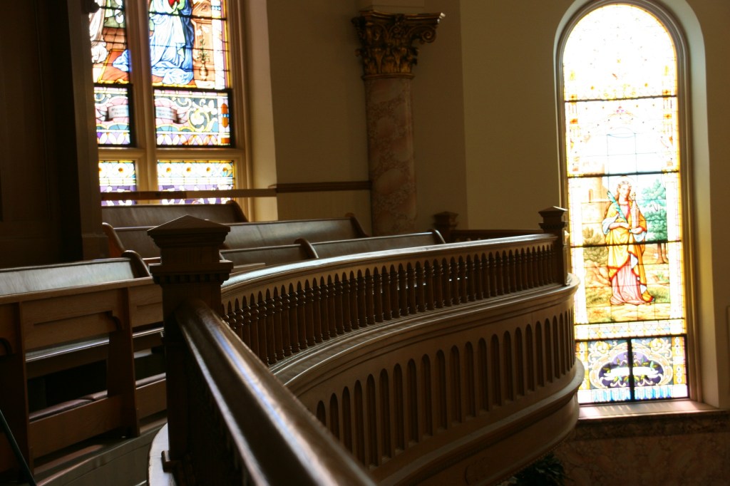 Beautiful morning light filters through stained glass onto the curving balcony railing.