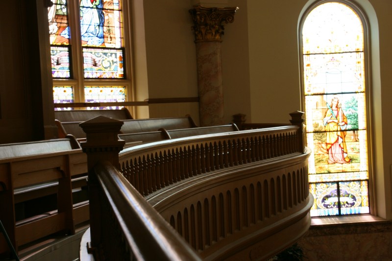 Beautiful morning light filters through stained glass onto the curving balcony railing.