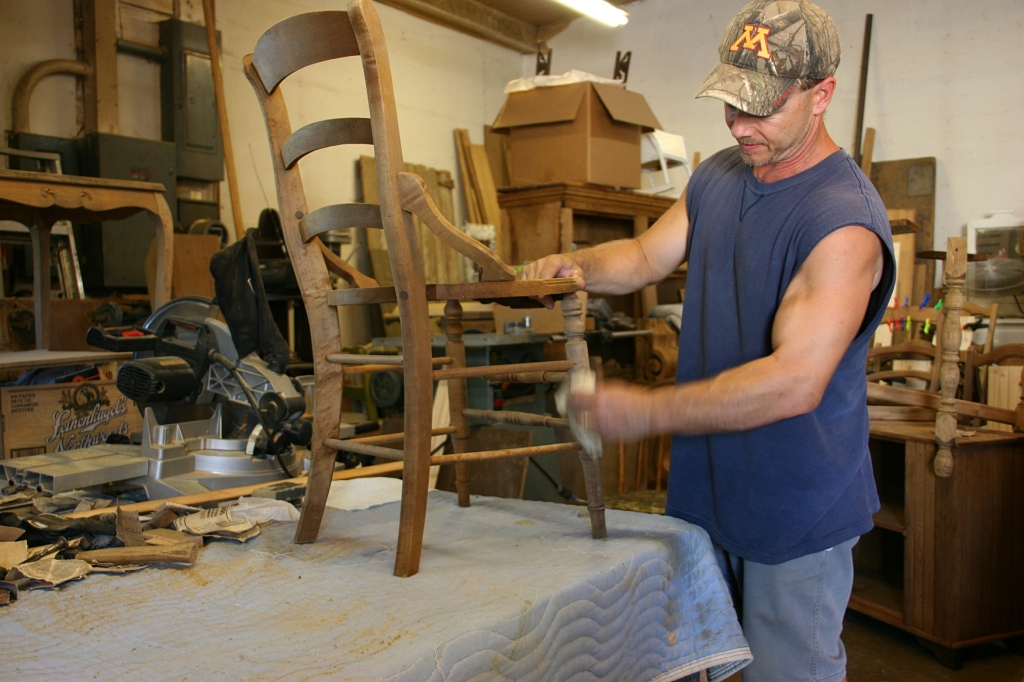 Jeff Lerum sands a chair in his shop, where he restores and repairs furniture.