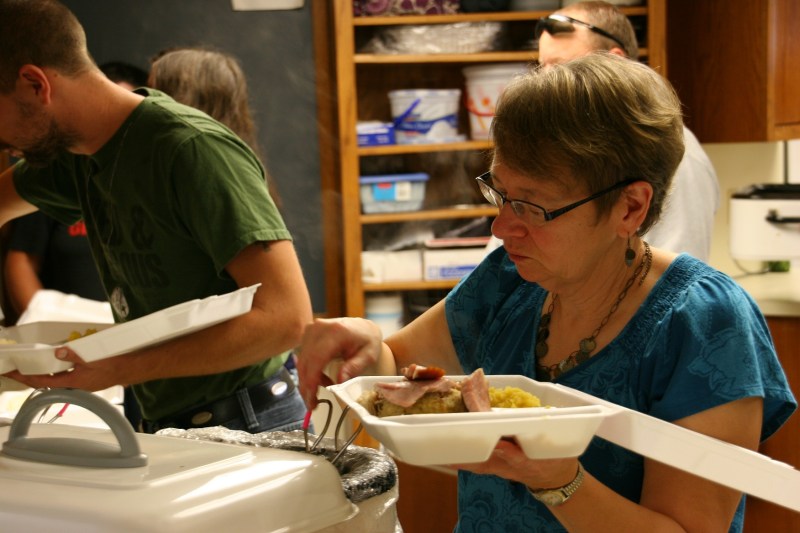 A member of the kitchen crew dishes up meals for take-out.