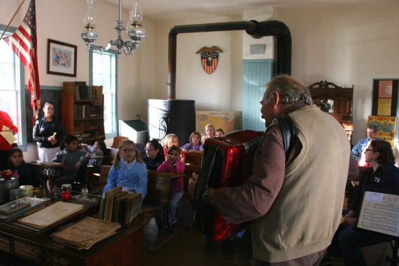 The one-room Pleasant Valley School quickly filled with students as the teacher led his class in songs.