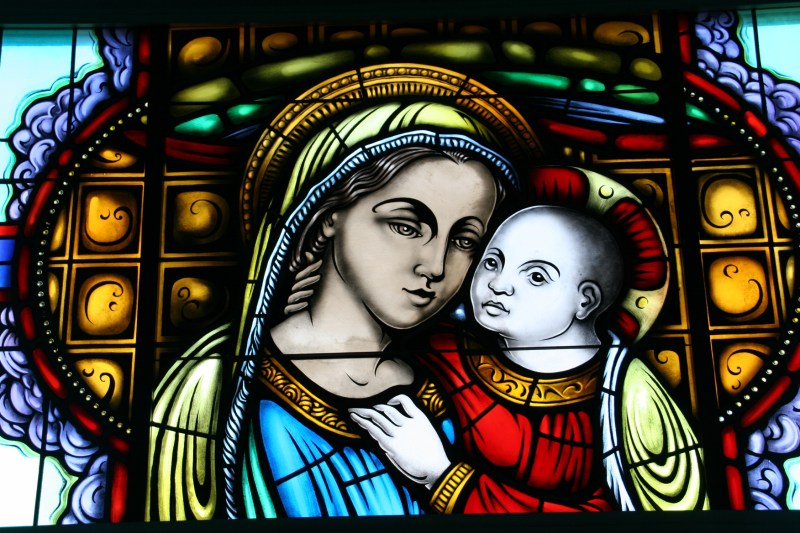 The stained glass windows inside the Mother of Good Cunsel Votive Chapel depict apparitions and titles of Our Blessed Mother.