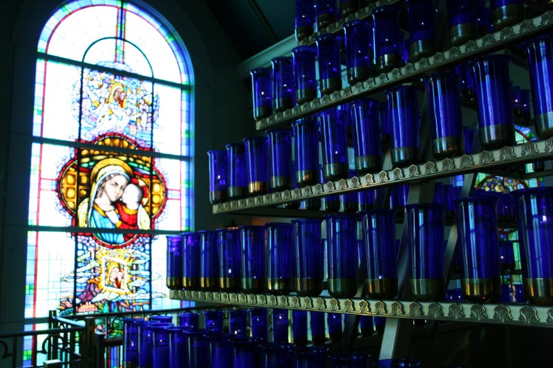 A rack holds 576 candles inside the Mother of Good Counsel Votive Chapel. Pilgrims, for a price, may have a candle lit. A lift allows lighting of the tiered candles stretching high into the chapel.