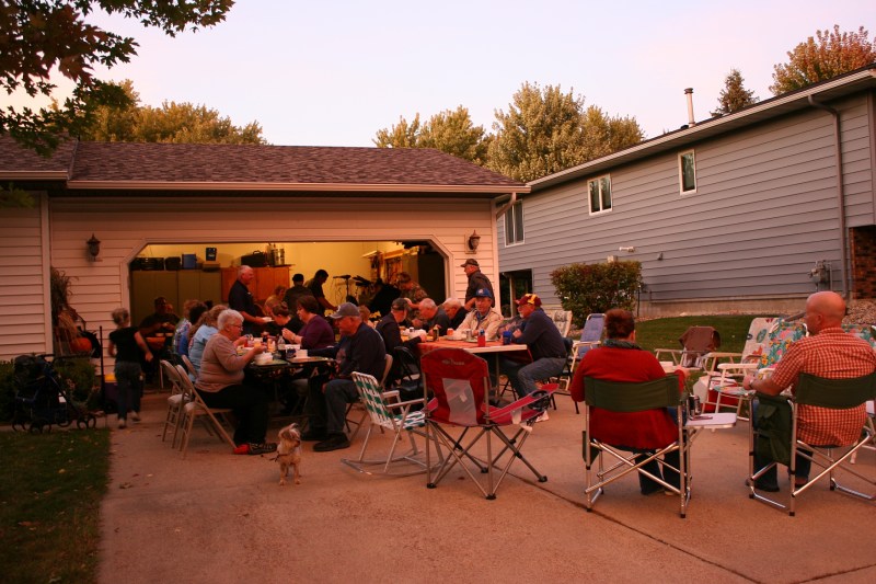 As the sun sets in southern Minnesota, guests gather on the driveway and in the garage to sample soups and chili.