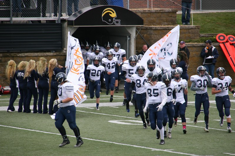 JCC players run through the sign and onto the field for the start of the second half.