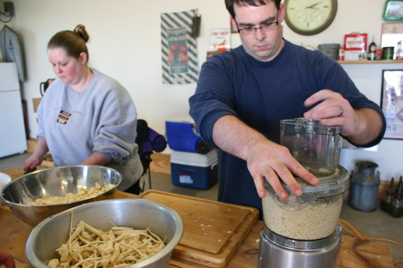 My niece cuts horseradish while her husband refines it in a food processor.