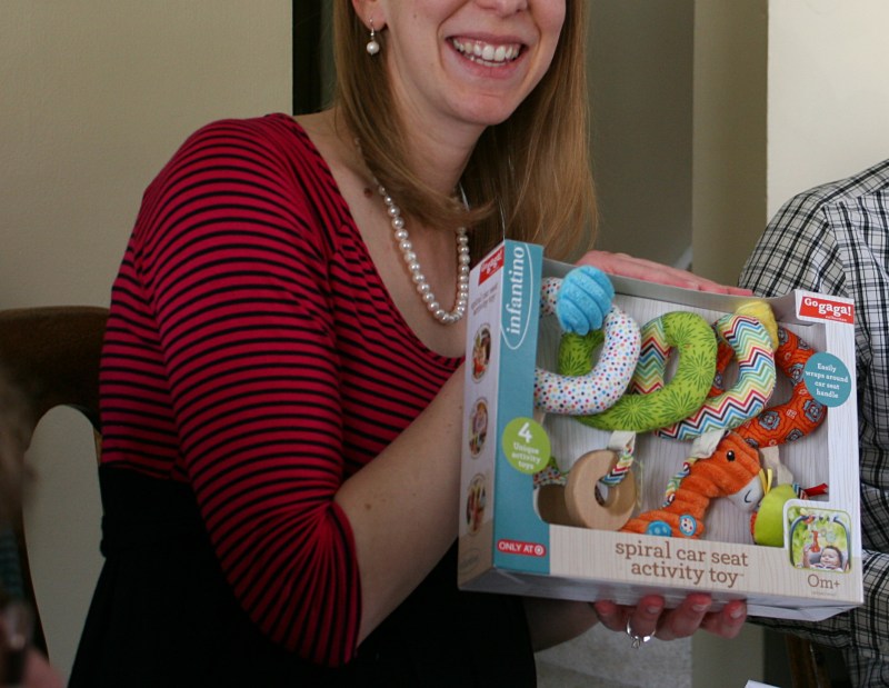 My daughter holds a colorful car seat activity toy for her daughter.
